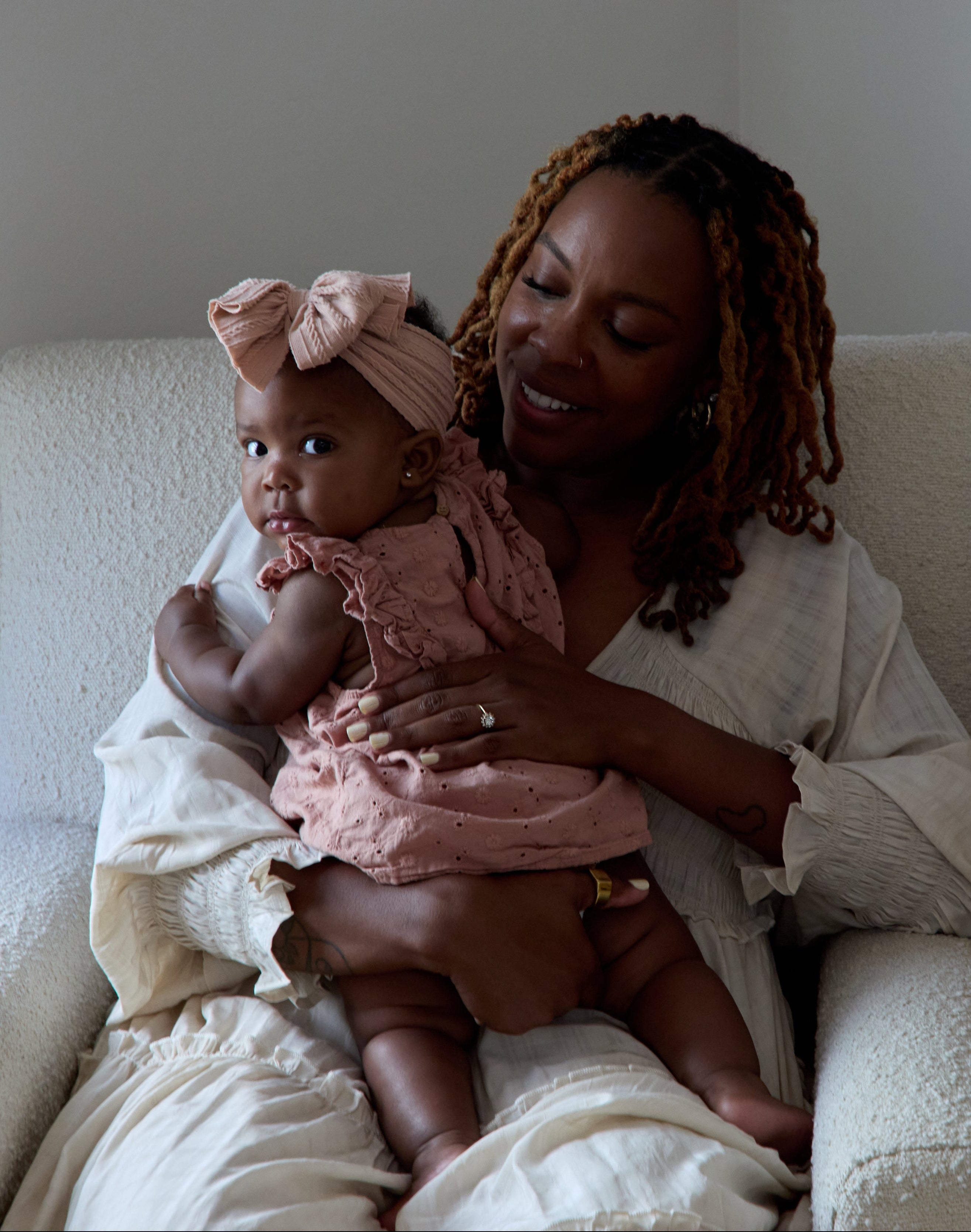 Woman holding a baby in a chair with a neutral background