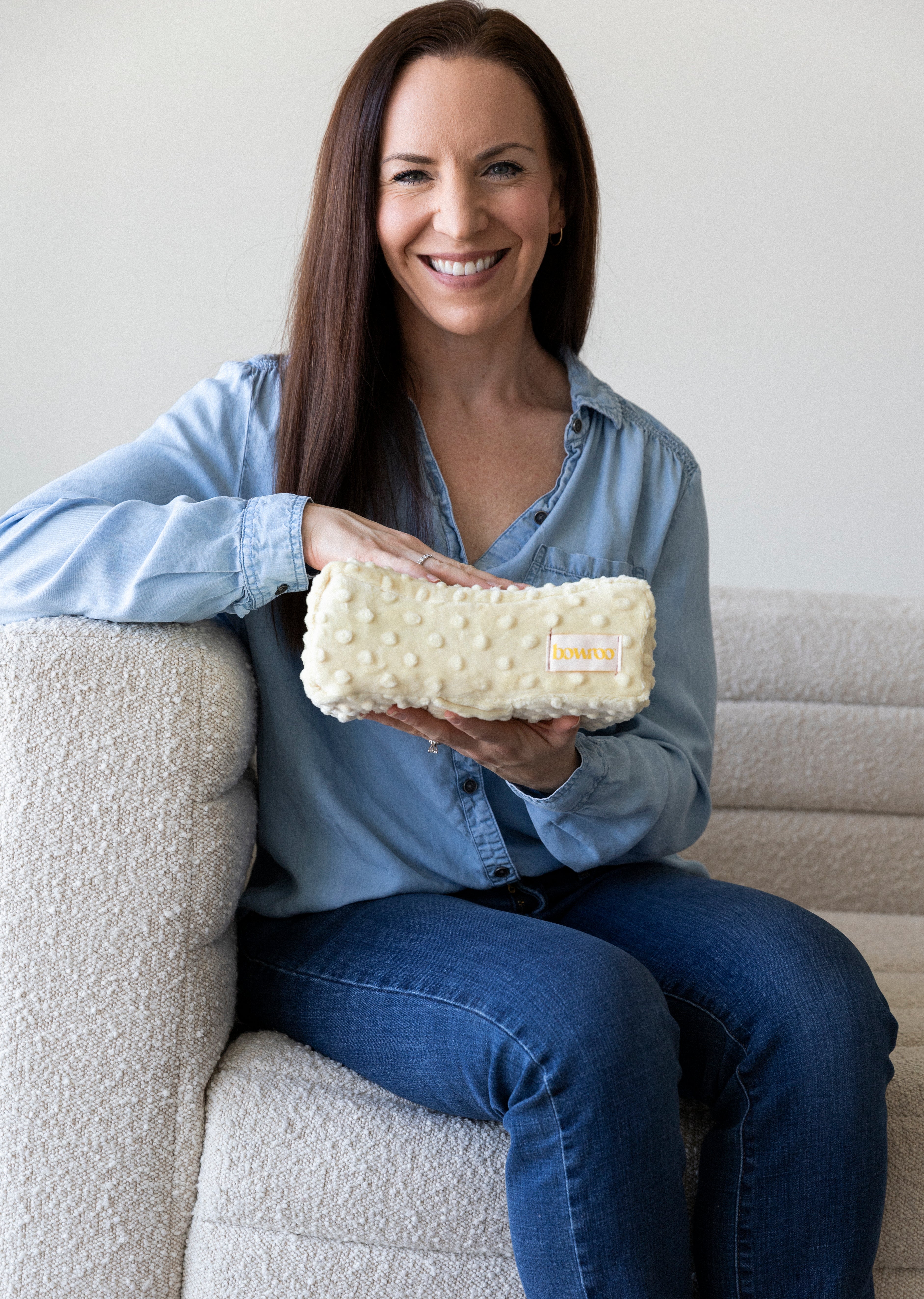 Amanda McVey Founder of Bowroo sitting on couch holding yellow pillow
